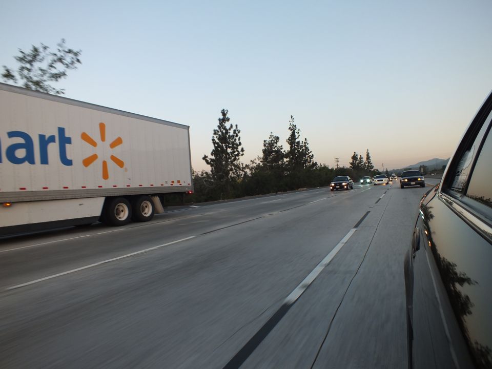 Walmart semi-truck trailer passing on left of freeway at dusk, oncoming traffic in distance