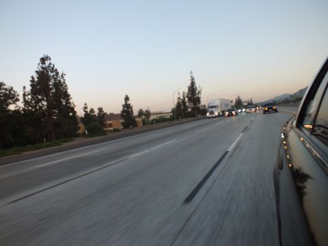 2003 Ford Crown Victoria - Twilight freeway traffic including a semi-truck, framed by a dark car body at the right edge.