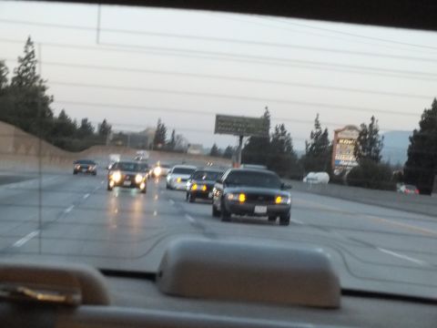 2003 Ford Crown Victoria - Through-windshield view of dusk freeway traffic with headlights on, dashboard in foreground.