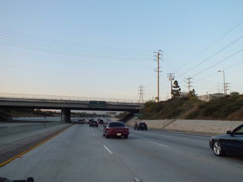 2003 Ford Crown Victoria - Twilight traffic heads toward a concrete overpass with a maroon car and dark coupe in view.