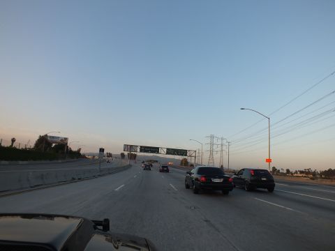 2003 Ford Crown Victoria - Twilight traffic on a sweeping freeway curve, black SUV at right and overhead sign gantry ahead.
