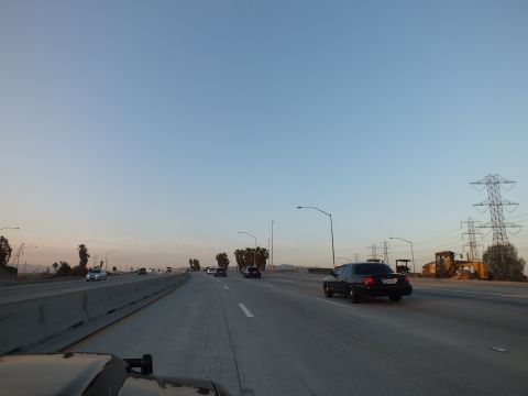 2003 Ford Crown Victoria - Black sedan rides the right lane on a twilight freeway lined by lampposts and a lone pylon.
