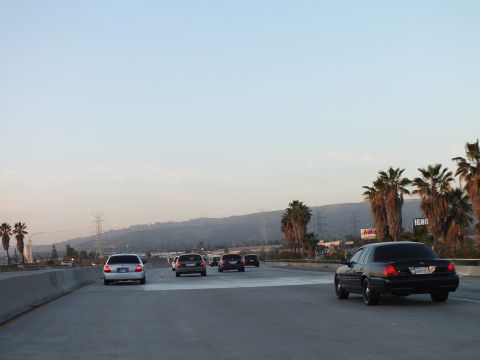 2003 Ford Crown Victoria - Several cars travel a multi-lane freeway with palms and a distant billboard reading IGN.
