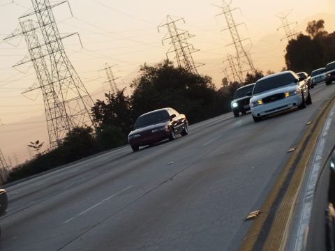 2003 Ford Crown Victoria - maroon sedan leads silver cars down the freeway past rows of power towers.