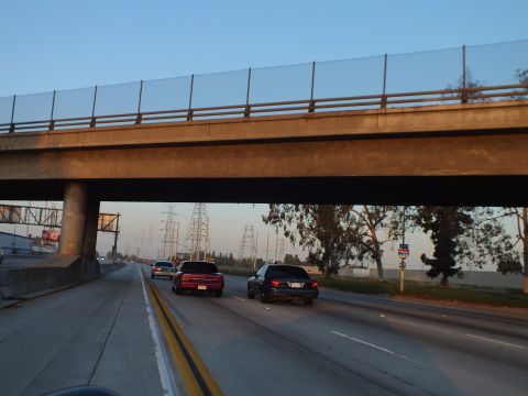 2003 Ford Crown Victoria - Two black sedans travel the freeway as it dips under a railed concrete overpass.