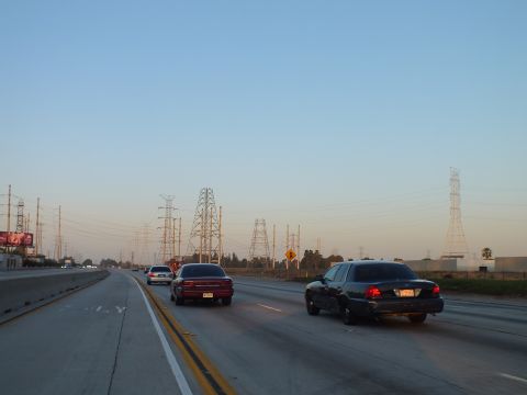 2003 Ford Crown Victoria - Cars cruising a wide highway near electrical transmission towers under a clear evening sky.