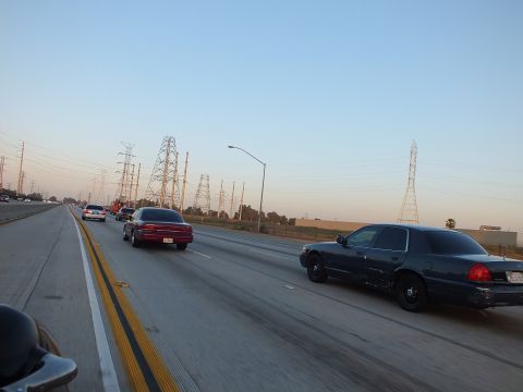 2003 Ford Crown Victoria - View over a rider's shoulder of traffic moving along an open highway at dusk.