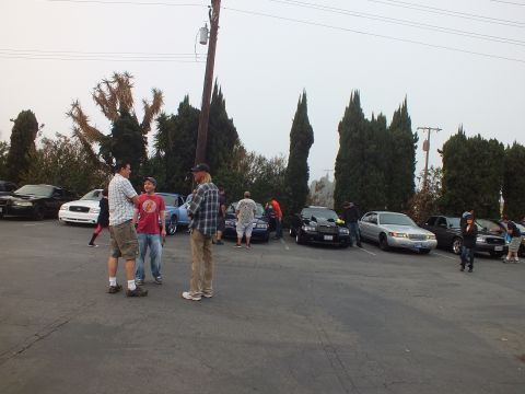 2003 Ford Crown Victoria - Attendees in casual clothes gather between rows of cars at a hazy outdoor meet.