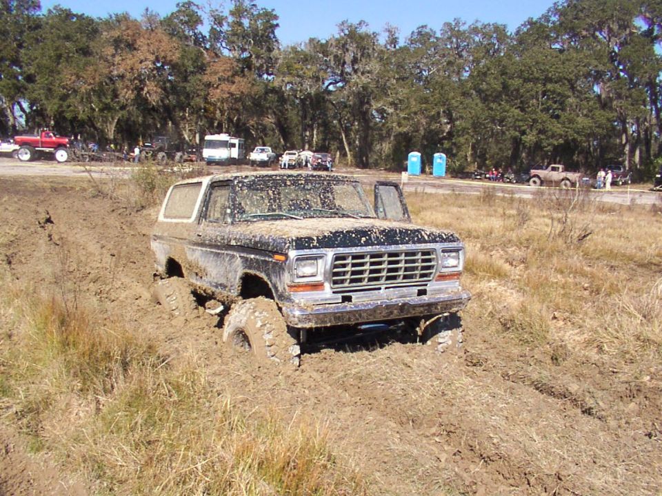 Mud-covered 1978 Ford Bronco stuck in mud, front 3/4 view