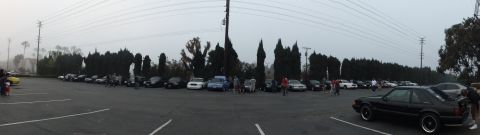 2003 Ford Crown Victoria - Wide shot of a meet with vehicles spread along a tree-lined lot at dusk.