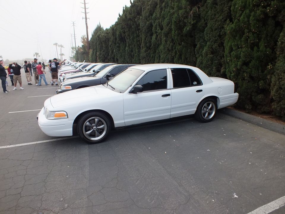 Side profile of lowered white Ford Crown Victoria parked on asphalt
