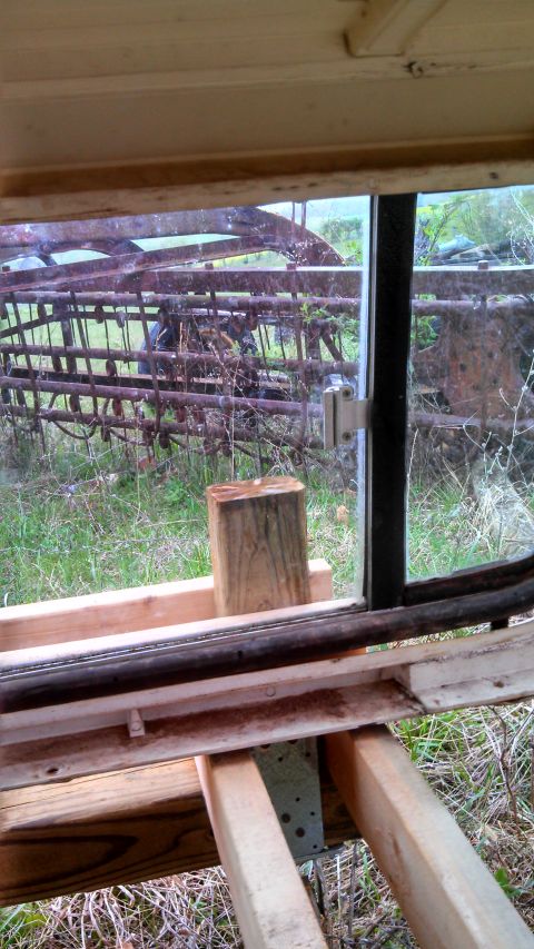 1979 Ford Bronco - Rusty farm equipment visible through a window, with wooden framing in the foreground.