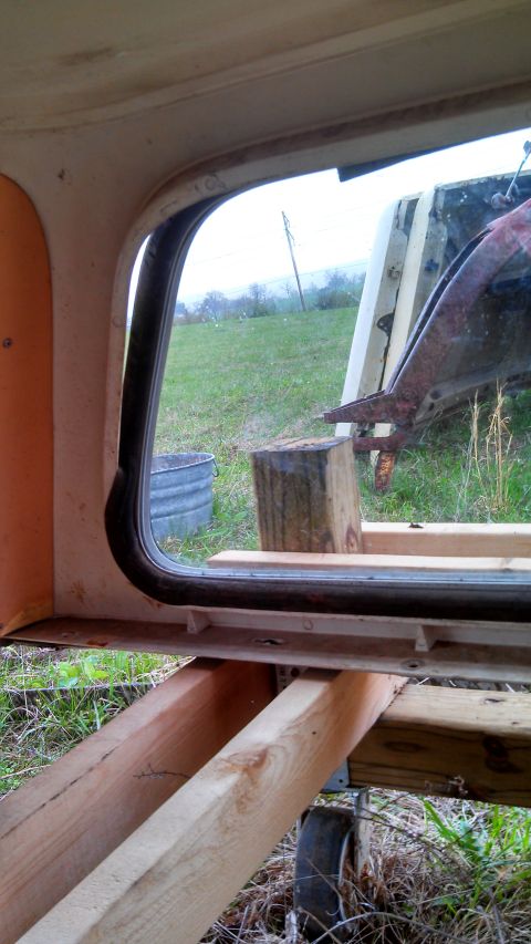 1979 Ford Bronco - The interior of a vehicle shows a window frame with exterior views of a field and some construction materials.