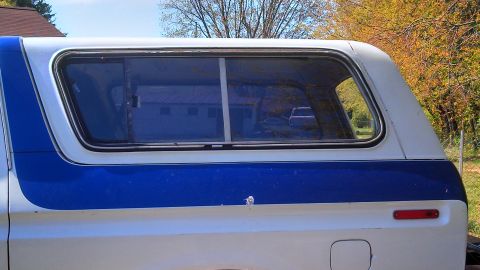 1979 Ford Bronco - 1979 Ford Bronco with a two-tone white and blue camper shell, showing the side profile and rear quarter panel.