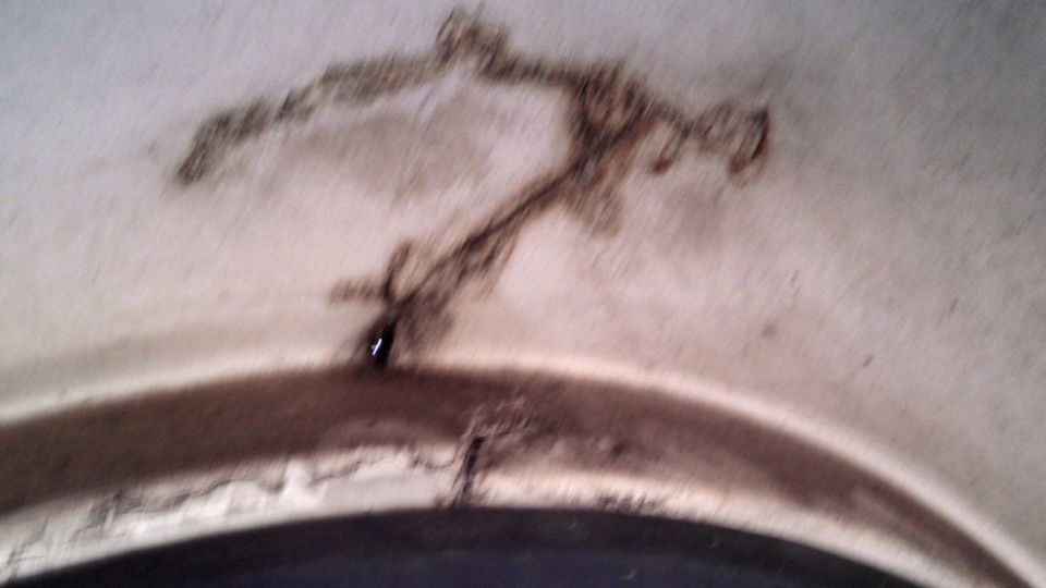 Close-up of rust and damage on an interior panel, possibly a wheel well