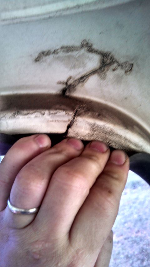 1979 Ford Bronco - A hand inspects a cracked white panel, revealing dirt and damage.