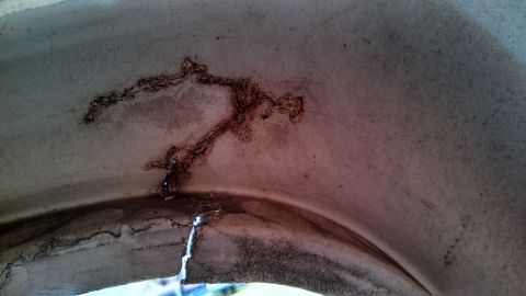 1979 Ford Bronco - Damage and staining are visible inside the wheel well of a vehicle.
