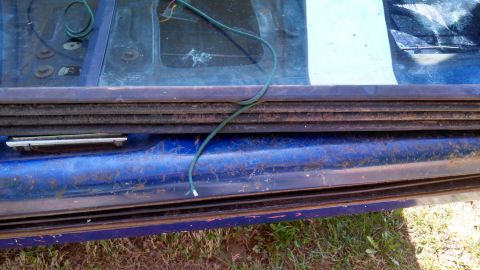 1979 Ford Bronco - Detail of a vehicle's door frame with exposed wiring and a rubber seal.