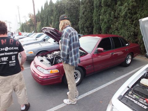 2003 Ford Crown Victoria - Dark red Crown Victoria with raised hood sits in the lot as a man in plaid looks over the engine.