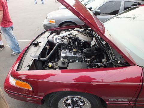 2003 Ford Crown Victoria - Open hood reveals a forced-induction engine; the maroon fender carries a CROWN VICTORIA badge.