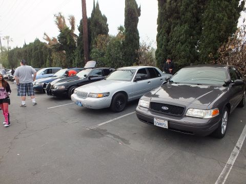 2003 Ford Crown Victoria - Gray Ford Crown Victoria and silver Mercury Grand Marquis parked among other sedans with onlookers