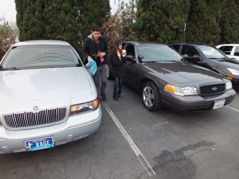 2003 Ford Crown Victoria - Silver Mercury Grand Marquis showing Nevada vanity plate RAGE next to a gray Ford Crown Victoria, people nearby