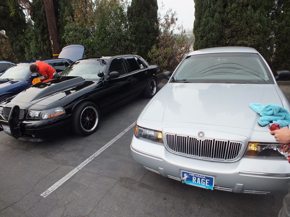 Black Crown Victoria with open hood beside silver Mercury Grand Marquis with RAGE plate