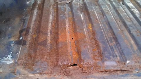 1979 Ford Bronco - The floor of a truck bed shows extensive rust damage and holes.
