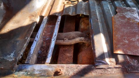 1979 Ford Bronco - The underside of a vehicle shows significant rust damage to the floor pan, exposing the fuel tank and exhaust system.