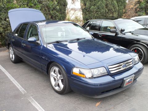 2003 Ford Crown Victoria - Lowered blue Ford Crown Victoria with chrome wheels, projector headlights and open trunk parked at a meet