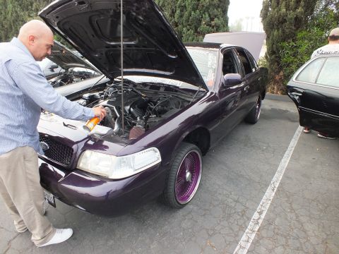 2003 Ford Crown Victoria - Owner sprays the engine bay of a purple Ford Crown Victoria sitting on purple wire wheels.