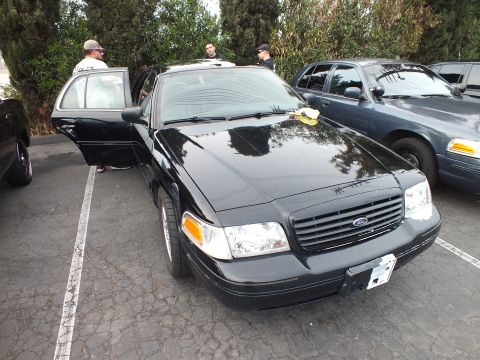 2003 Ford Crown Victoria - Black Ford Crown Victoria photographed front-on with driver door open among rows of sedans.