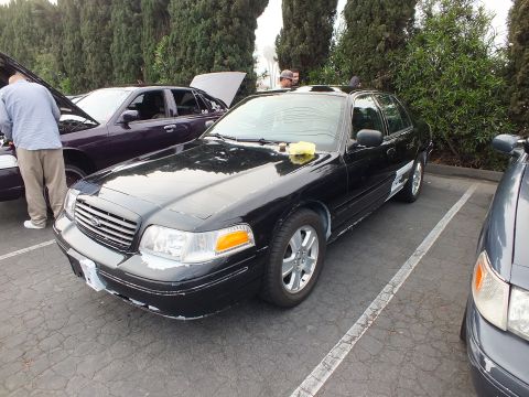 2003 Ford Crown Victoria - Black Ford Crown Victoria on alloy wheels parked among other sedans at an outdoor gathering.