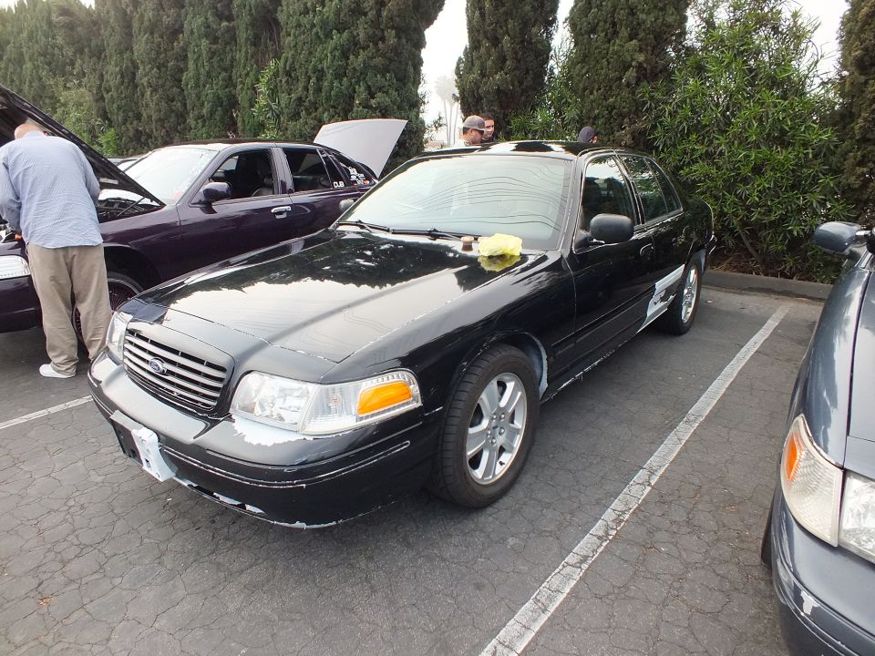 Black Ford Crown Victoria parked at car meet, alloy wheels, hooded cars in background