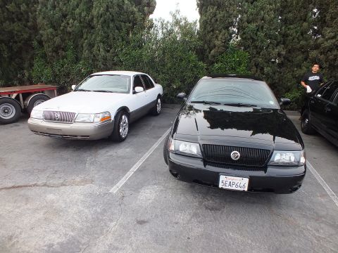 2003 Ford Crown Victoria - White two-tone Mercury Grand Marquis beside a black Mercury Marauder in a parking lot.