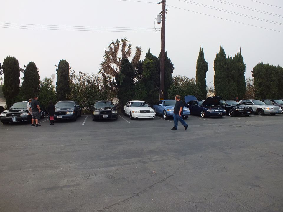 Full-size sedans in white blue and black parked nose-out with a man walking by