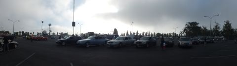 2003 Ford Crown Victoria - wide panoramic view of various cars parked across a large open lot under a cloudy sky at a car gathering.