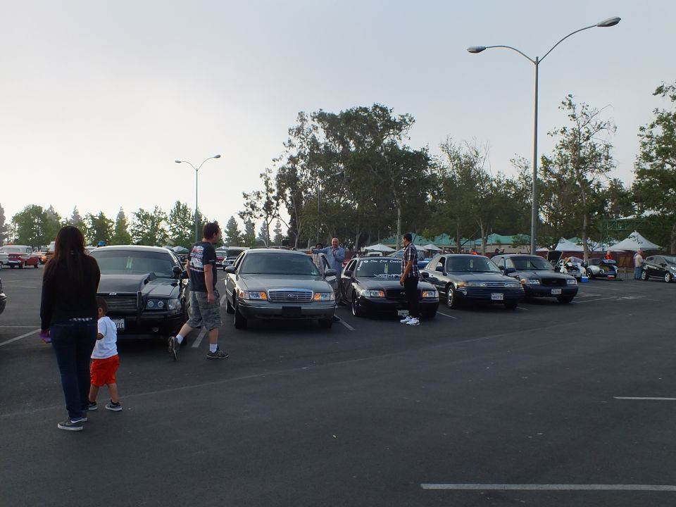 Full-size sedans parked nose-out with people walking through a large lot