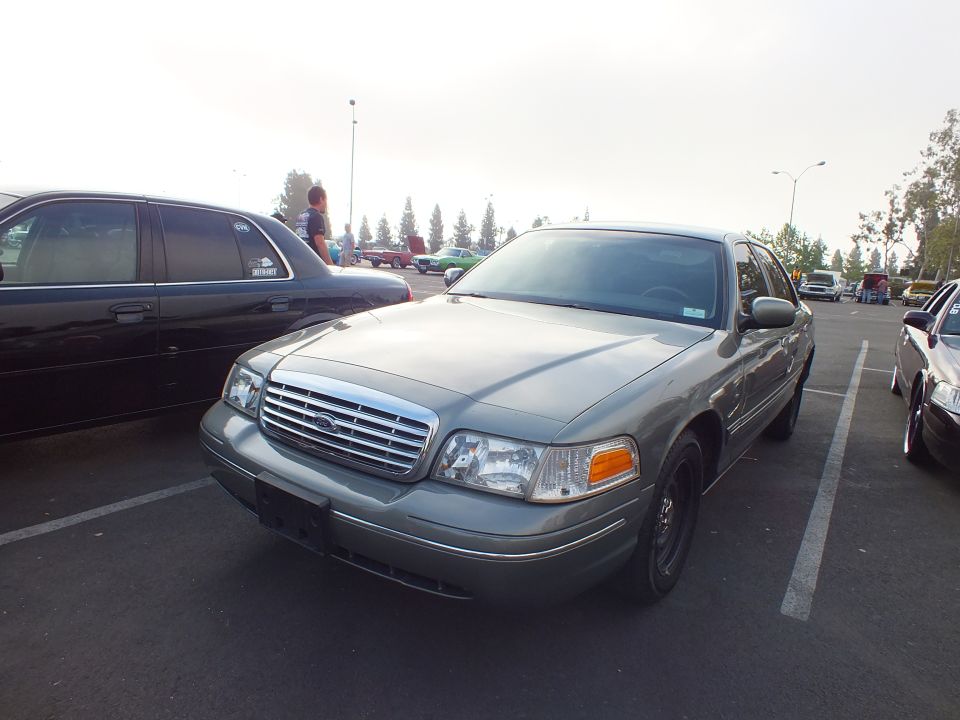 Gray-green Ford full-size sedan front three-quarter view in parking lot