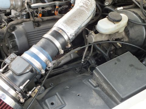 2003 Ford Crown Victoria - Close-up of a silver heat-wrapped intake tube joined by a blue silicone coupler next to the brake master-cylinder reservoir.