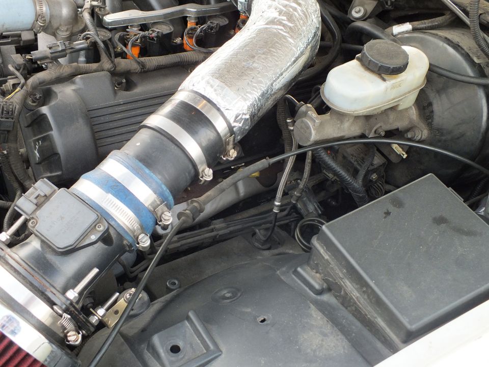 Close-up of silver heat-wrapped intake tube with blue coupler and brake reservoir