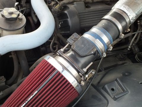 2003 Ford Crown Victoria - red Spectre cone air filter clamped to an intake tube with a mass-air-flow sensor and blue coolant hose in the engine bay.