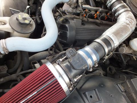 2003 Ford Crown Victoria - red Spectre cone air filter on a chrome intake tube routed past a blue coolant hose inside an engine bay.