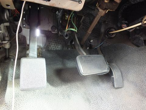 2003 Ford Crown Victoria - Close-up of newly fitted clutch and brake pedals under the dashboard with exposed wiring and gray floor matting.