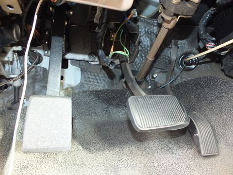 2003 Ford Crown Victoria - Three under-dash pedals with green, orange and white wiring routed around the steering column on gray carpet.