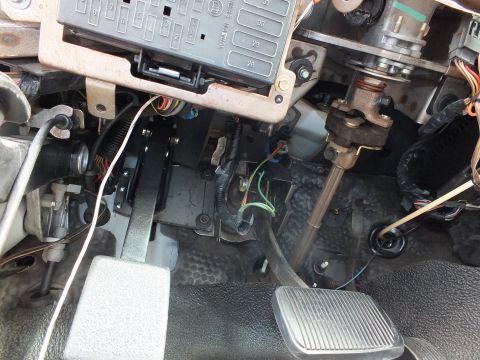 2003 Ford Crown Victoria - Under-dash view showing a fuse panel, steering column shaft and a pedal surrounded by loose colorful wiring.