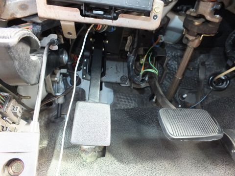 2003 Ford Crown Victoria - Two under-dash pedals beneath the steering column with a relay block and bundled colorful wiring overhead.