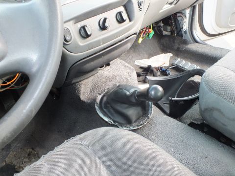 2003 Ford Crown Victoria - manual transmission shifter with a black boot newly installed in the floor tunnel of a sedan with gray cloth seats.