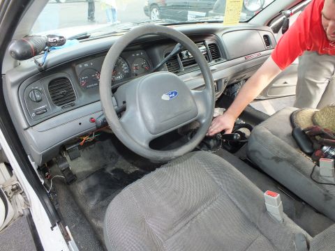 2003 Ford Crown Victoria - Ford Crown Victoria interior with gray steering wheel and cloth bench seat as a man in a red shirt reaches inside.