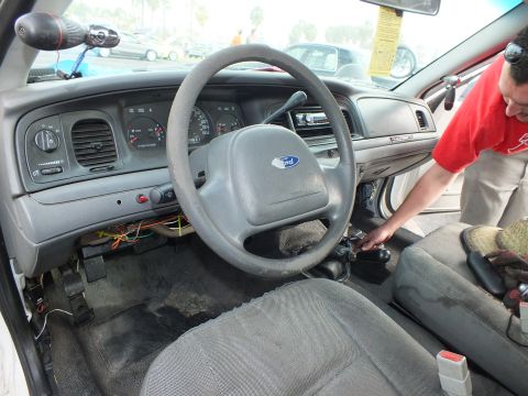 2003 Ford Crown Victoria - Ford Crown Victoria interior with a manual shifter and gray steering wheel as a man in red works on the conversion.